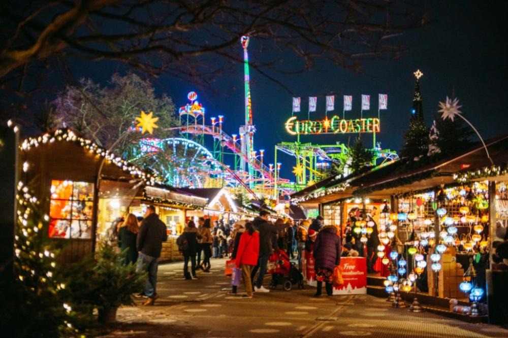 Hyde Park Winter Wonderland: Colourful fairground rides and festive market stalls illuminated at night at Hyde Park Winter Wonderland in London.